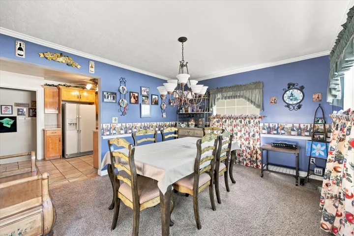Dining area with a multi-light chandelier, crown molding, and an arched window