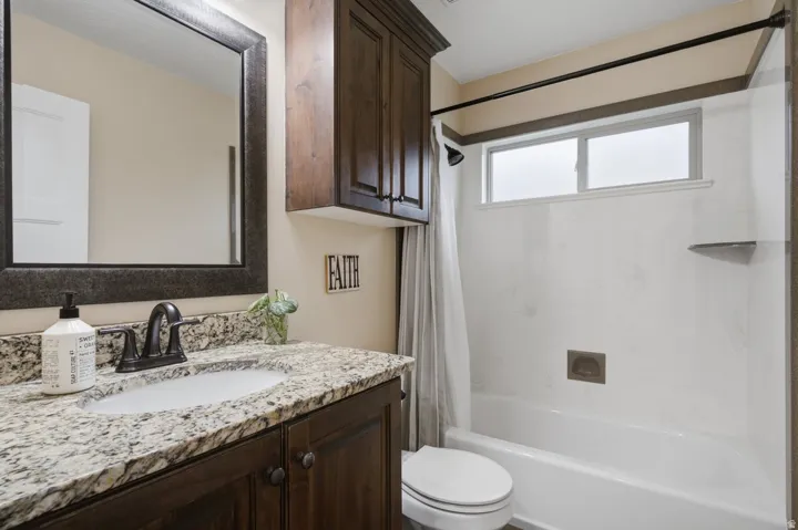 Vanity with granite countertop, dark wood-finish cabinetry, and oil-rubbed bronze fixtures