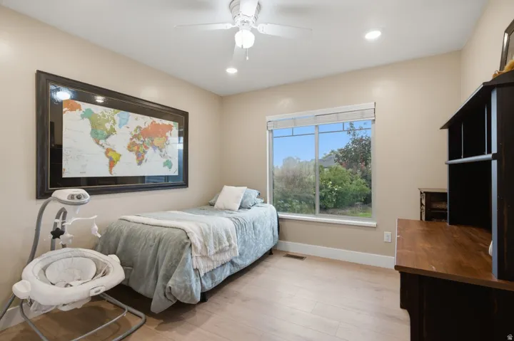Spacious room featuring wood-finish flooring, a large window, recessed lighting, and a ceiling fan