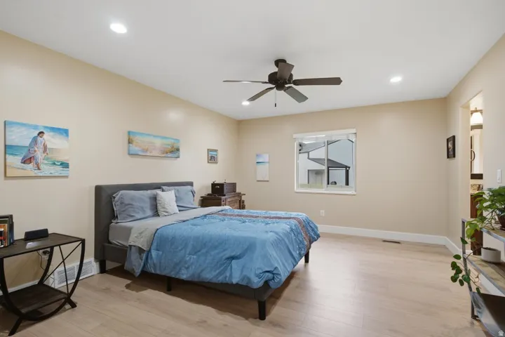 Recessed ceiling lighting, a ceiling fan, and light wood-finish flooring