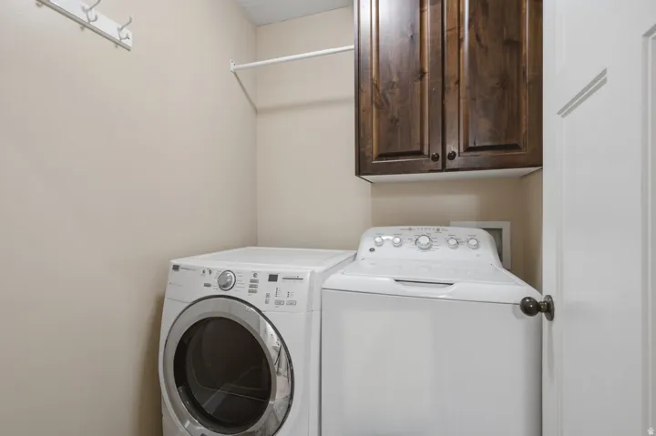 Dark wood-finish cabinetry, white wall-mounted drying rod, white wall-mounted coat rack, and white paneled door