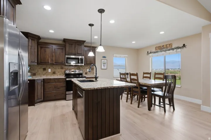 Open-concept kitchen and dining area featuring wood-finish flooring, recessed lighting, and a kitchen island with pendant lights