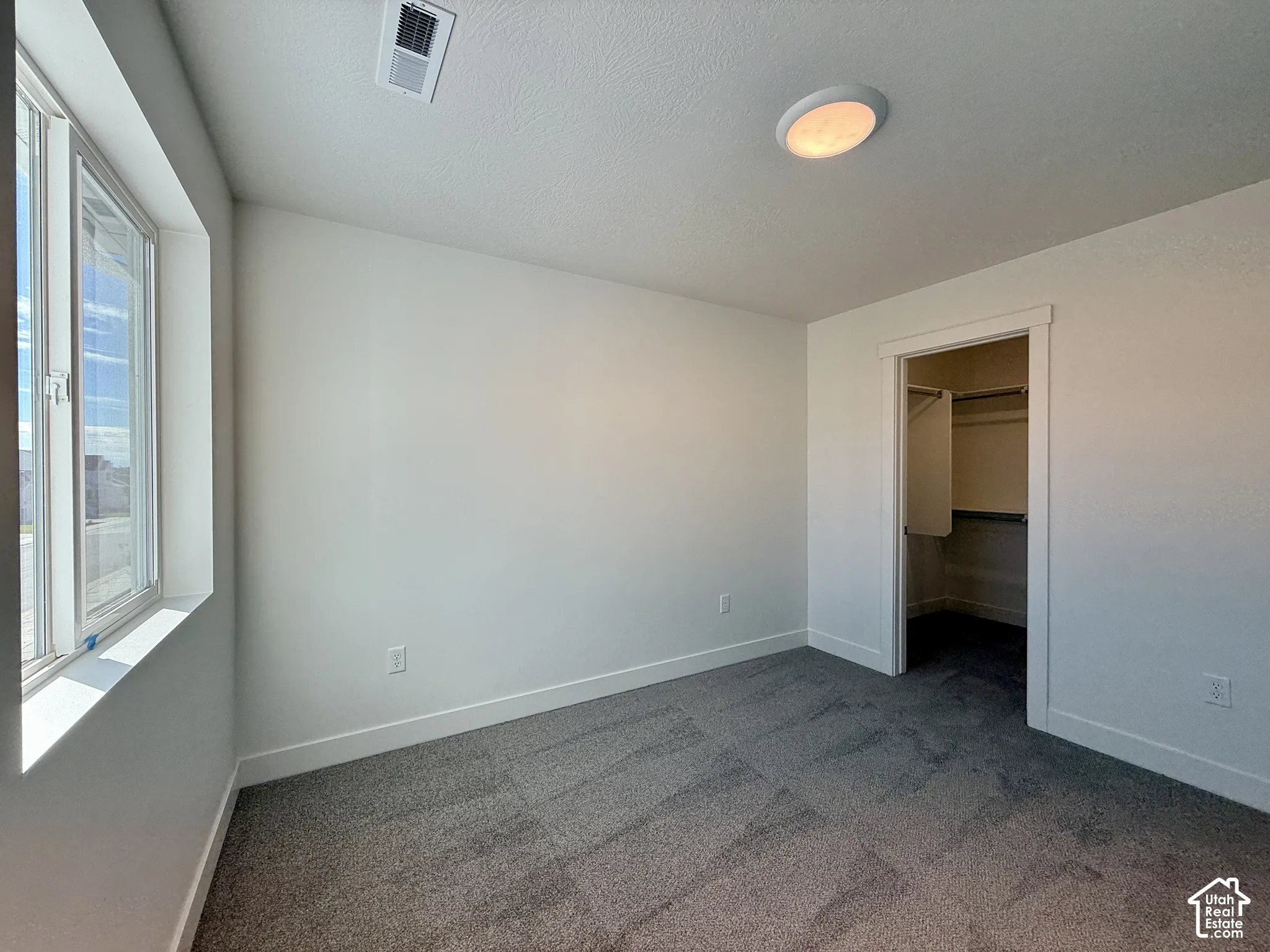 Neutral-toned carpeting, high-gloss window trim, crisp wall finishes, and a walk-in closet with built-in metal shelving