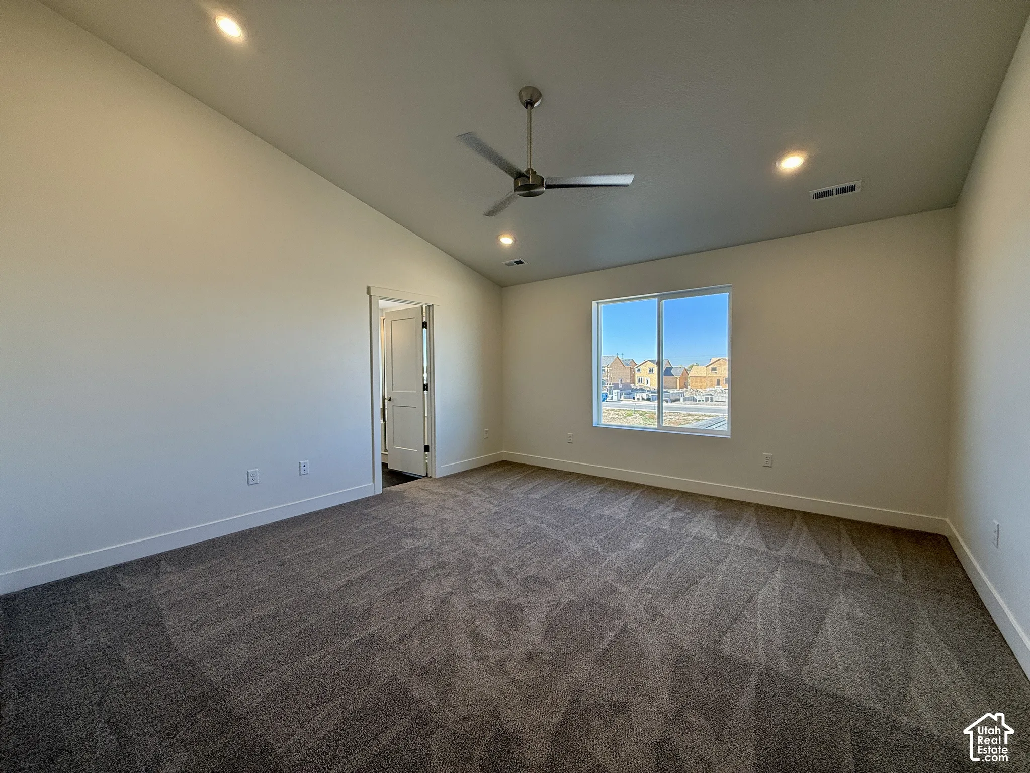 Vaulted ceilings featuring recessed lighting and a central ceiling fan, neutral wall-to-wall carpeting, and a large single-pane window