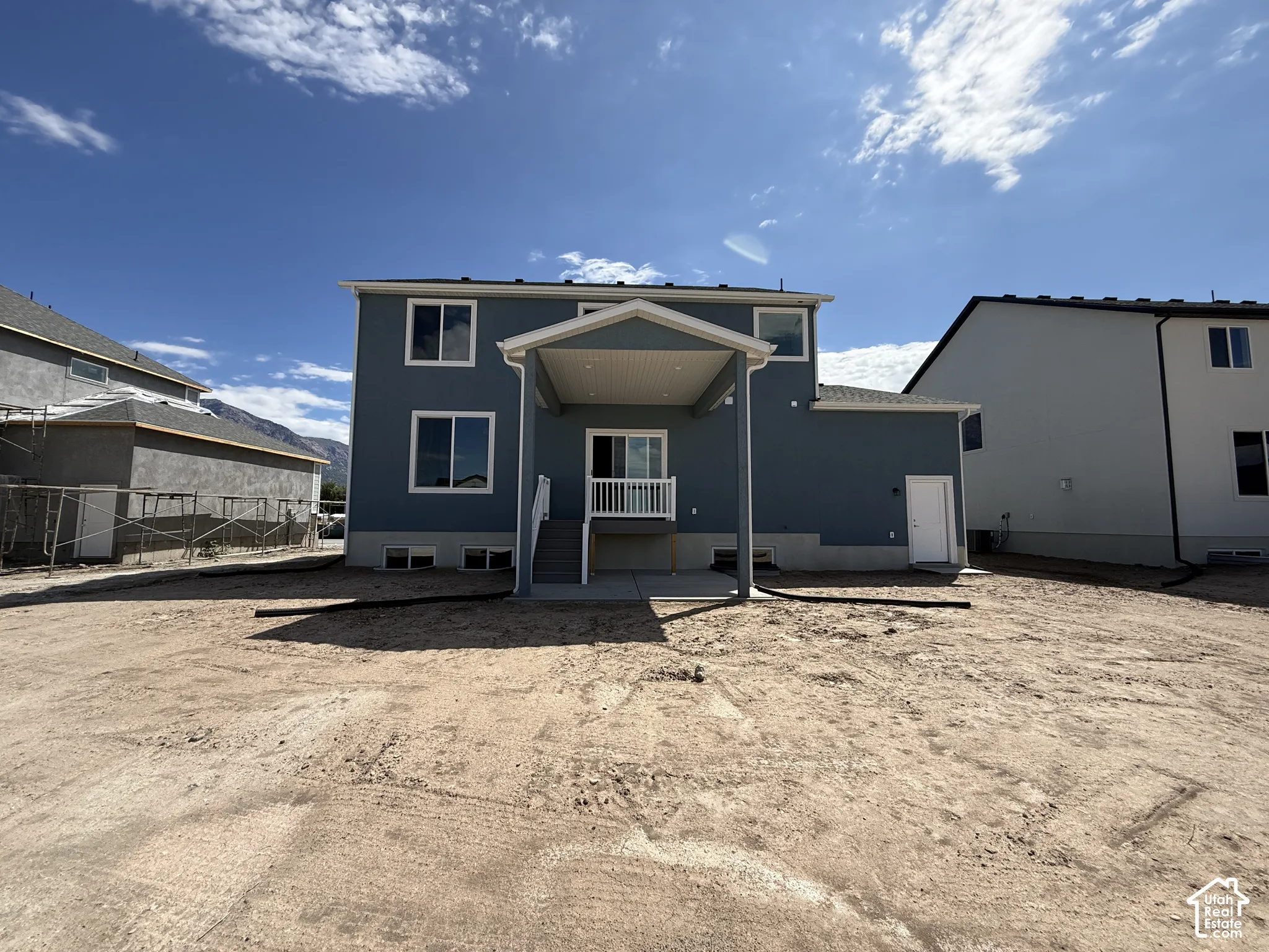 Rear exterior featuring blue siding, white window trim, a covered patio, and a sliding glass door