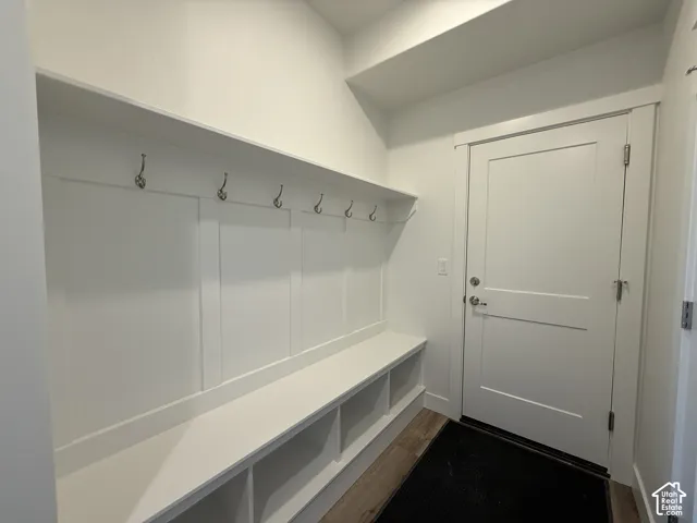 Built-in entryway bench with storage cubbies, decorative wall paneling, and a row of five coat hooks