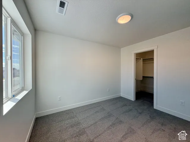 Neutral-toned carpeting, high-gloss window trim, crisp wall finishes, and a walk-in closet with built-in metal shelving