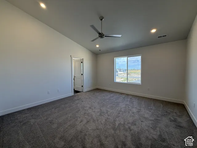 Vaulted ceiling with recessed lighting and a ceiling fan, dark carpet, and a large window