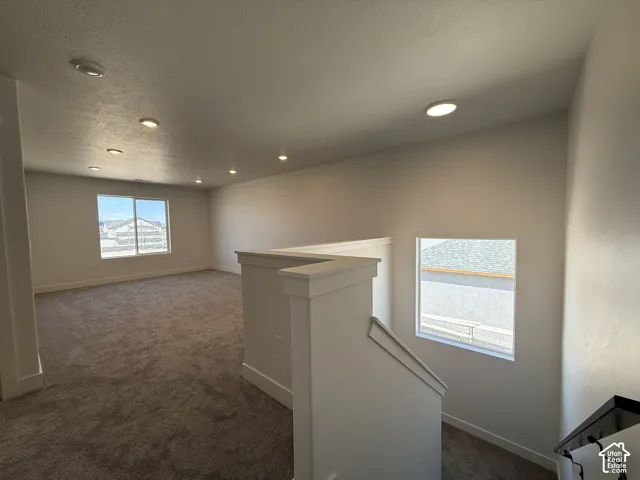 Spacious loft area featuring neutral carpeting, abundant recessed lighting, and multiple windows