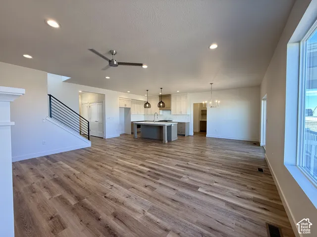 Open-concept kitchen featuring a center island, recessed lighting, wood-finish flooring, metal staircase railing, and pendant lighting