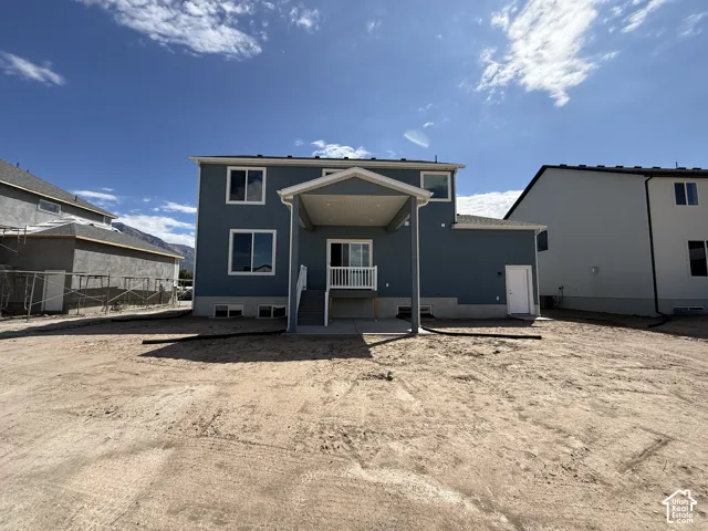 Rear exterior featuring blue siding, white window trim, a covered patio, and a sliding glass door