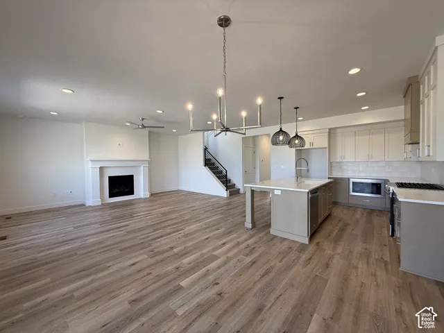 Open-concept living space featuring wood-finish flooring, a contemporary fireplace, and recessed lighting
