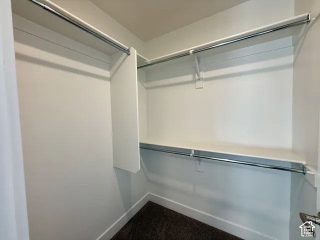 Walk-in storage space featuring multi-level metal hanging rods and white shelving