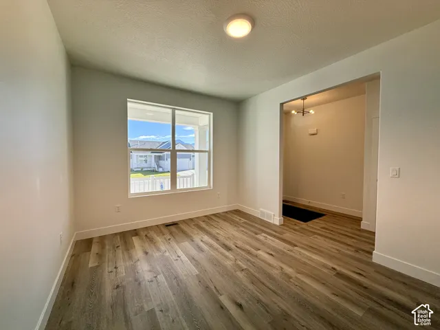 Interior room featuring wood-finish flooring, a large picture window, a neutral wall color palette, and a circular flush-mount ceiling light fixture