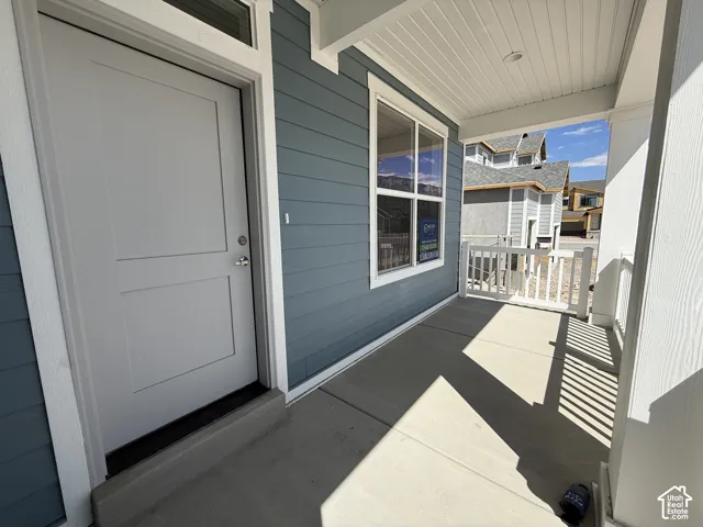 Covered front porch with concrete flooring and white railing