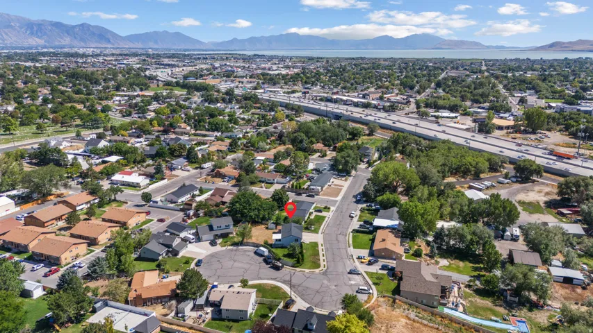 Aerial perspective of a residential neighborhood with distant mountains and a large body of water under a clear sky