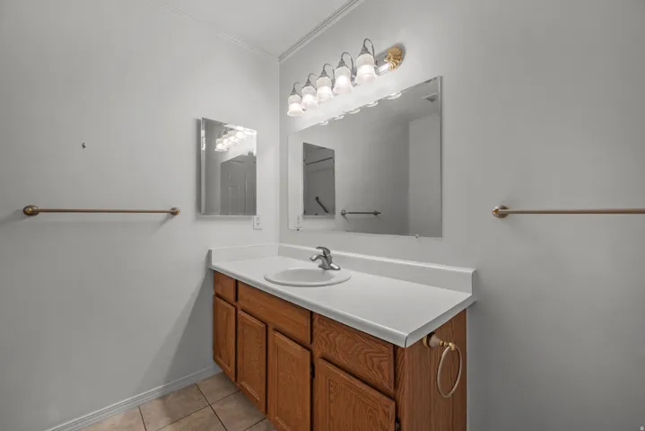Single vanity with wood-finish cabinetry, white countertop, and integrated sink
