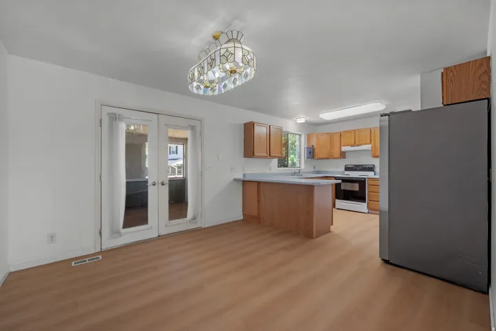 Wood-finish flooring throughout, French doors with glass panels, recessed and overhead lighting, wood cabinetry, and a kitchen island