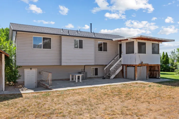 Rear exterior featuring a screened porch, exterior staircase, lower-level entry, and concrete patio