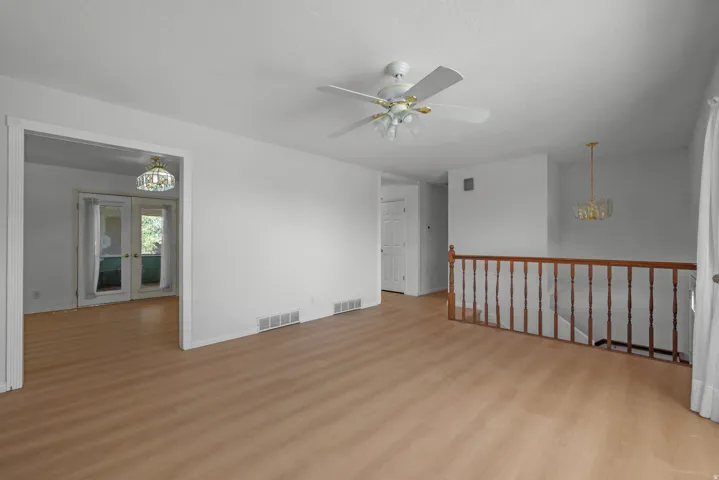 Wood-finish flooring throughout, white painted walls, ceiling fan, recessed lighting, and a wood railing