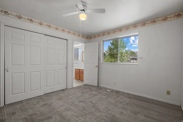 White paneled bi-fold closet doors, ceiling fan with integrated lighting, and a window providing natural light