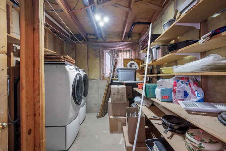 Laundry area with exposed wood framing, concrete flooring, and built-in shelving