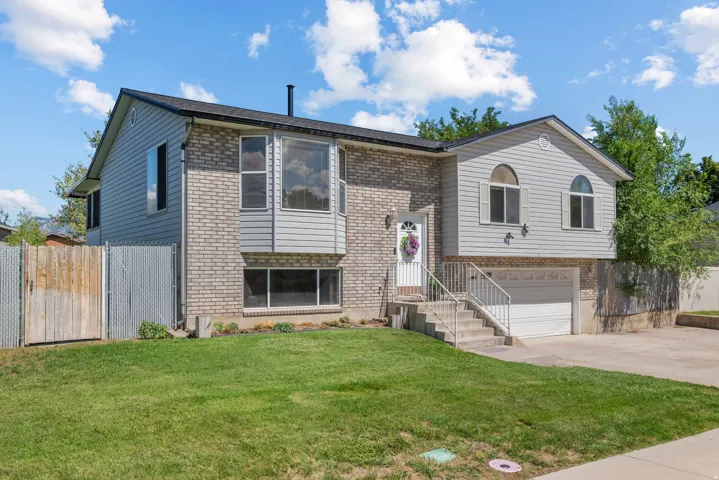 Split-level residence featuring a brick and siding exterior, an integrated garage, and a bay window