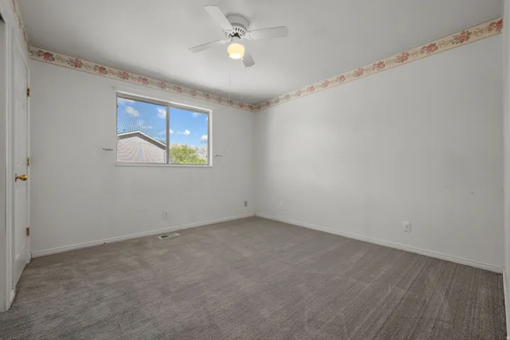 Neutral wall tones with a ceiling fan light fixture, carpeted flooring, and a sliding window
