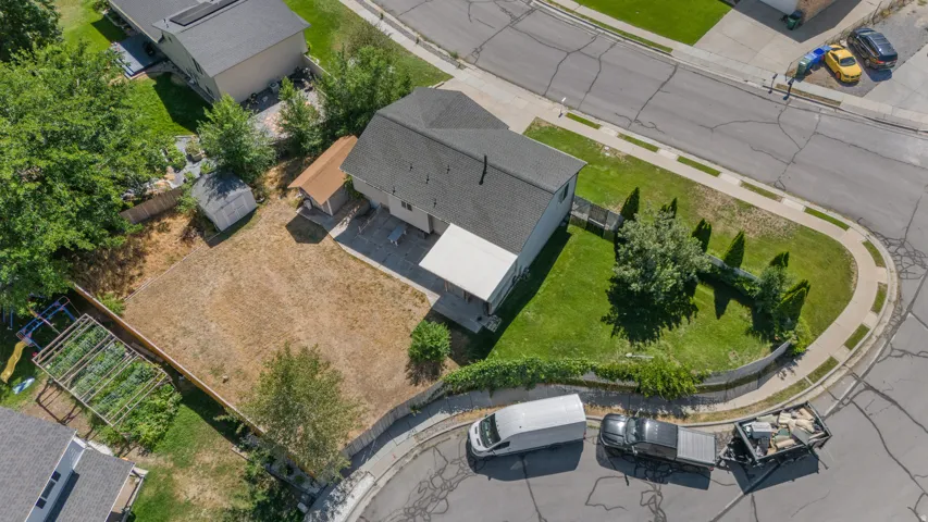 Large lot with extensive green space, mature trees, and a storage shed