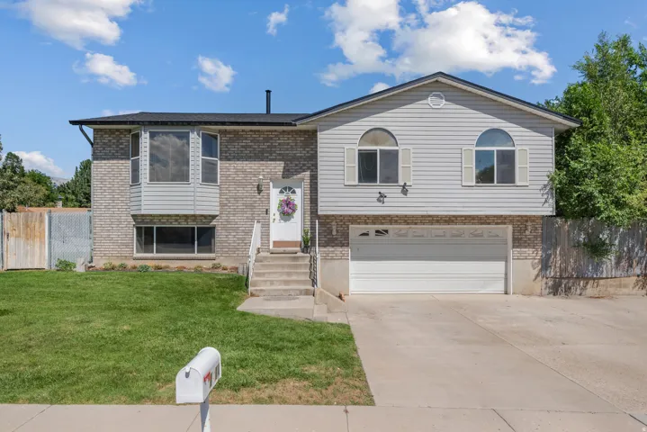 Two-story residence featuring a brick and siding exterior, bay window, arched windows with shutters, attached garage, and a concrete driveway