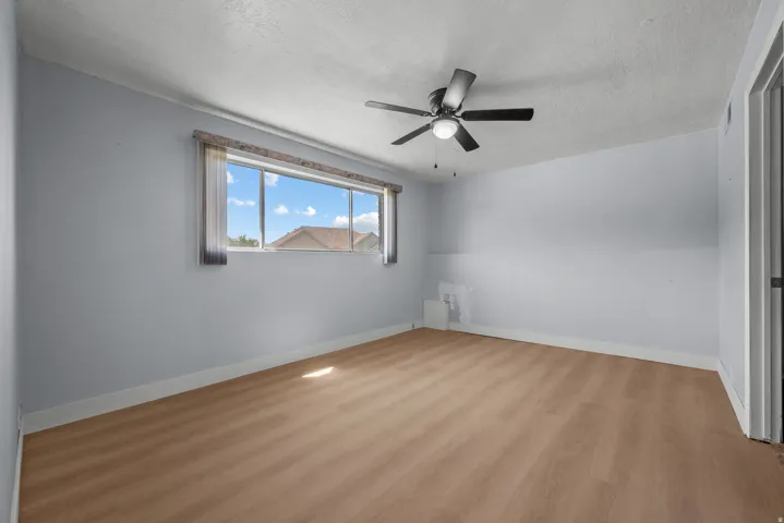 Wood-finish flooring with a ceiling fan and a window