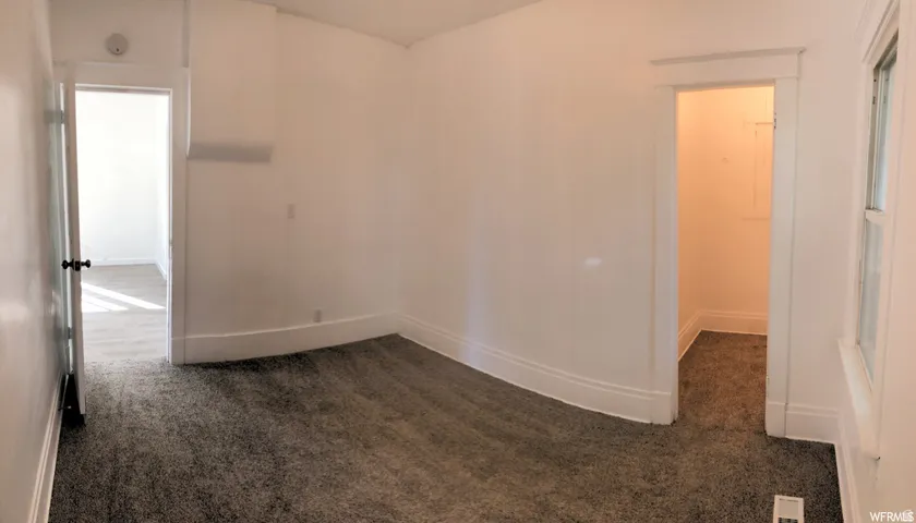 White walls, grey carpet, window with white trim, and white door frames