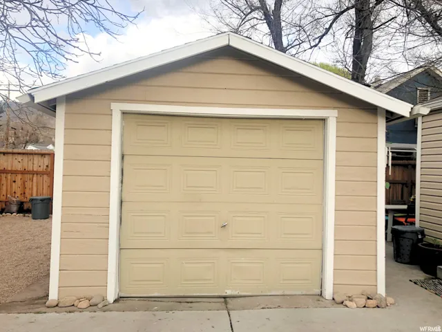 Single-car garage featuring a paneled door, horizontal siding, and a gabled roofline