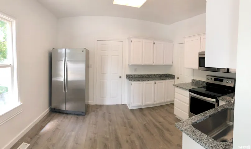 Kitchen featuring white cabinetry, granite-finish countertops, wood-finish flooring, stainless steel appliances, and a rectangular sink