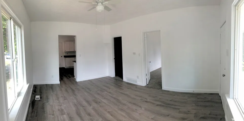 Wood-finish flooring, white walls, white trim, and a ceiling fan
