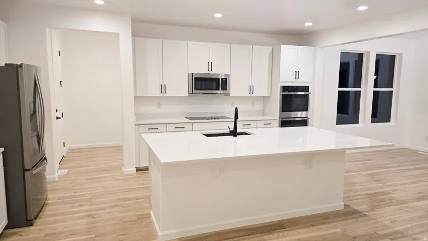Gourmet kitchen with white cabinetry, stainless steel appliances, and a large central island
