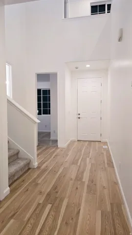 Two-story foyer featuring wood-finish flooring, recessed lighting, and a paneled entry door