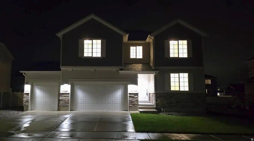Two-story residence featuring a gabled roofline, stone veneer accents, and multiple windows
