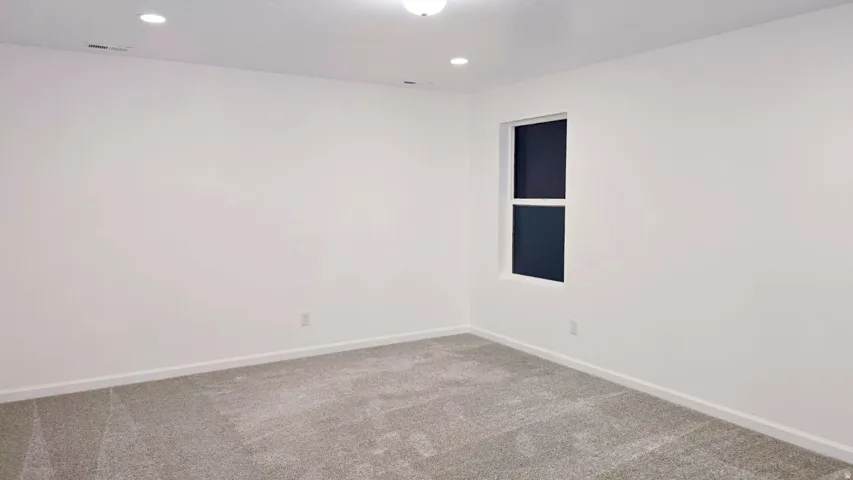 Recessed ceiling lighting, a single window, and light gray carpeting