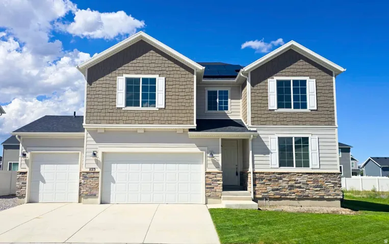 Modern two-story exterior with a two-car garage, stone and shake siding accents, and solar panels