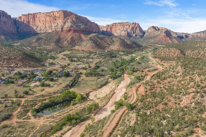 Expansive desert landscape featuring red rock mountains and a winding dry riverbed