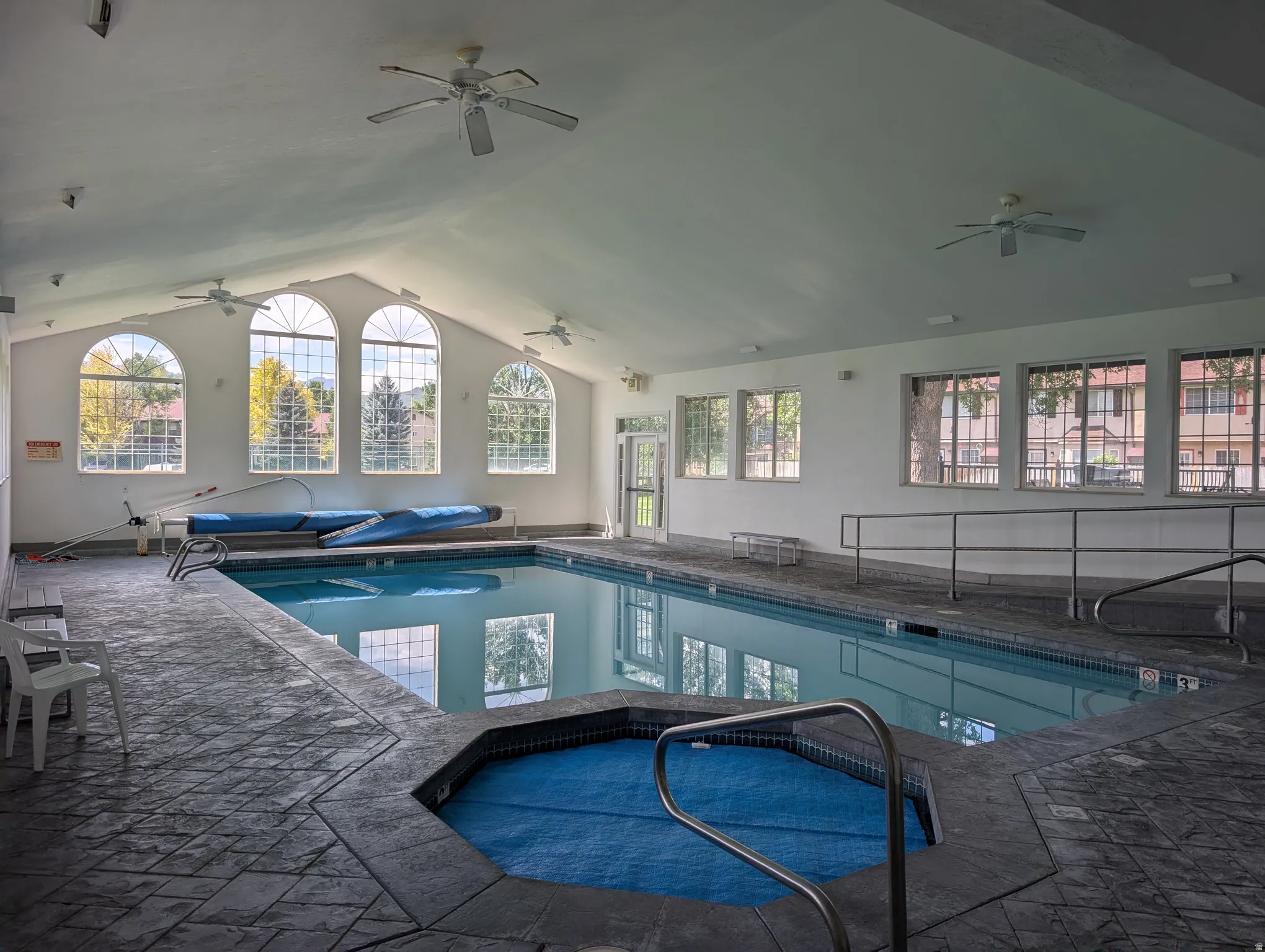 Indoor swimming pool featuring an integrated hot tub and vaulted ceilings