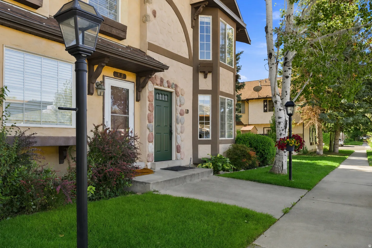 Front entrance featuring a green door with stone surround, a bay window, and a paved walkway