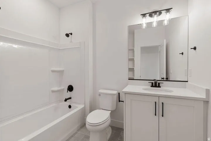 Contemporary bathroom featuring a white vanity with dual handles, quartz countertop, and integrated sink