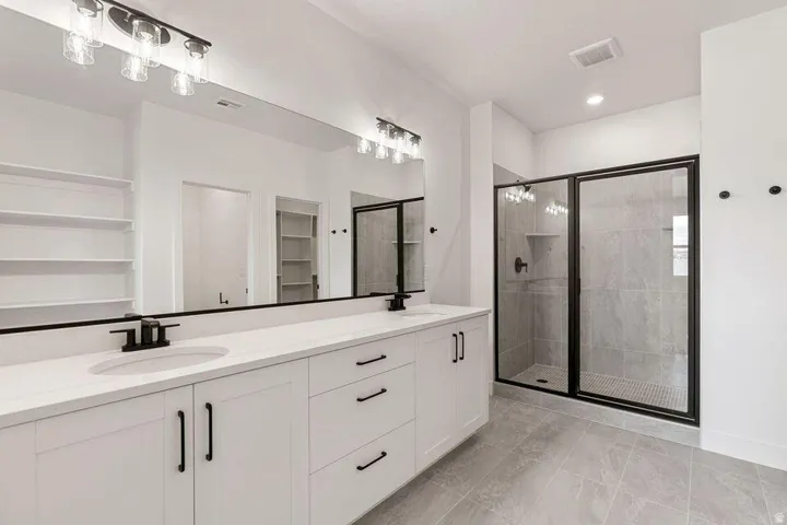 Double vanity with white cabinetry, matte black hardware, and an expansive mirror