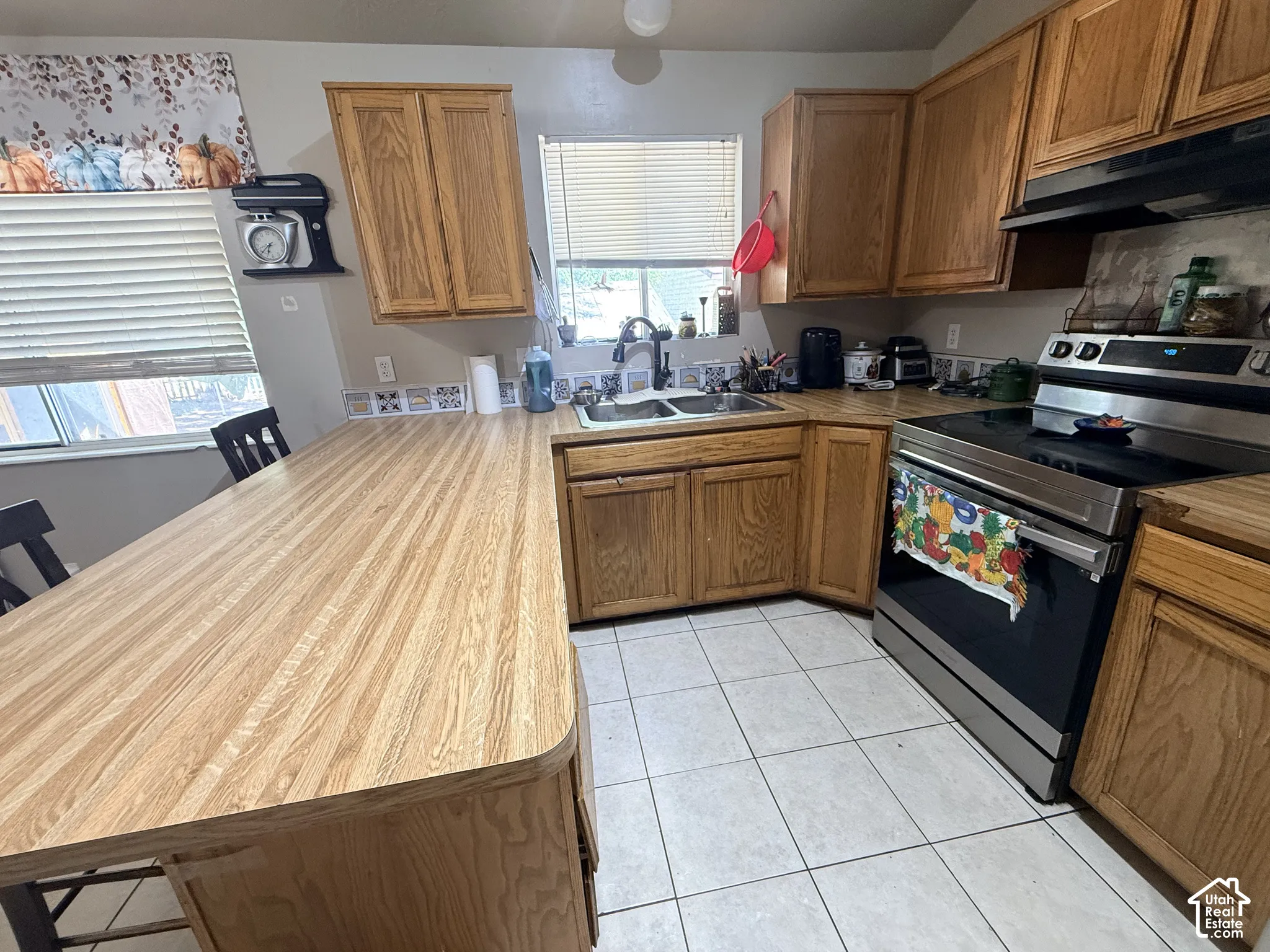 Kitchen featuring wood-finish cabinetry, a stainless steel range, and tile flooring