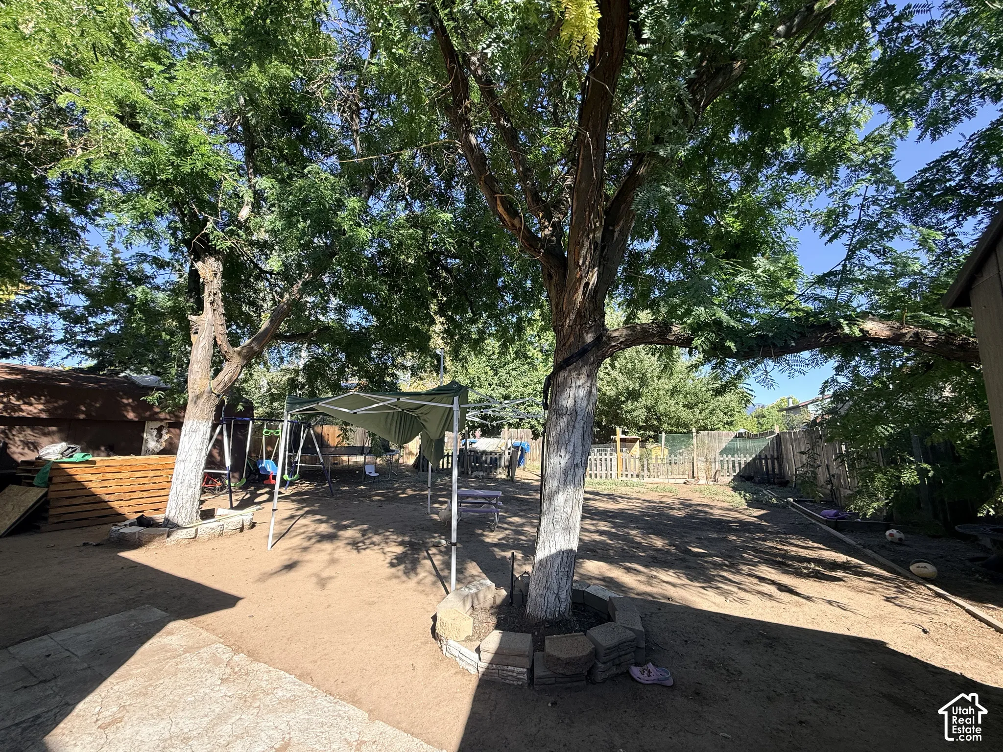 Expansive yard with mature trees, providing natural shade, and a surrounding privacy fence