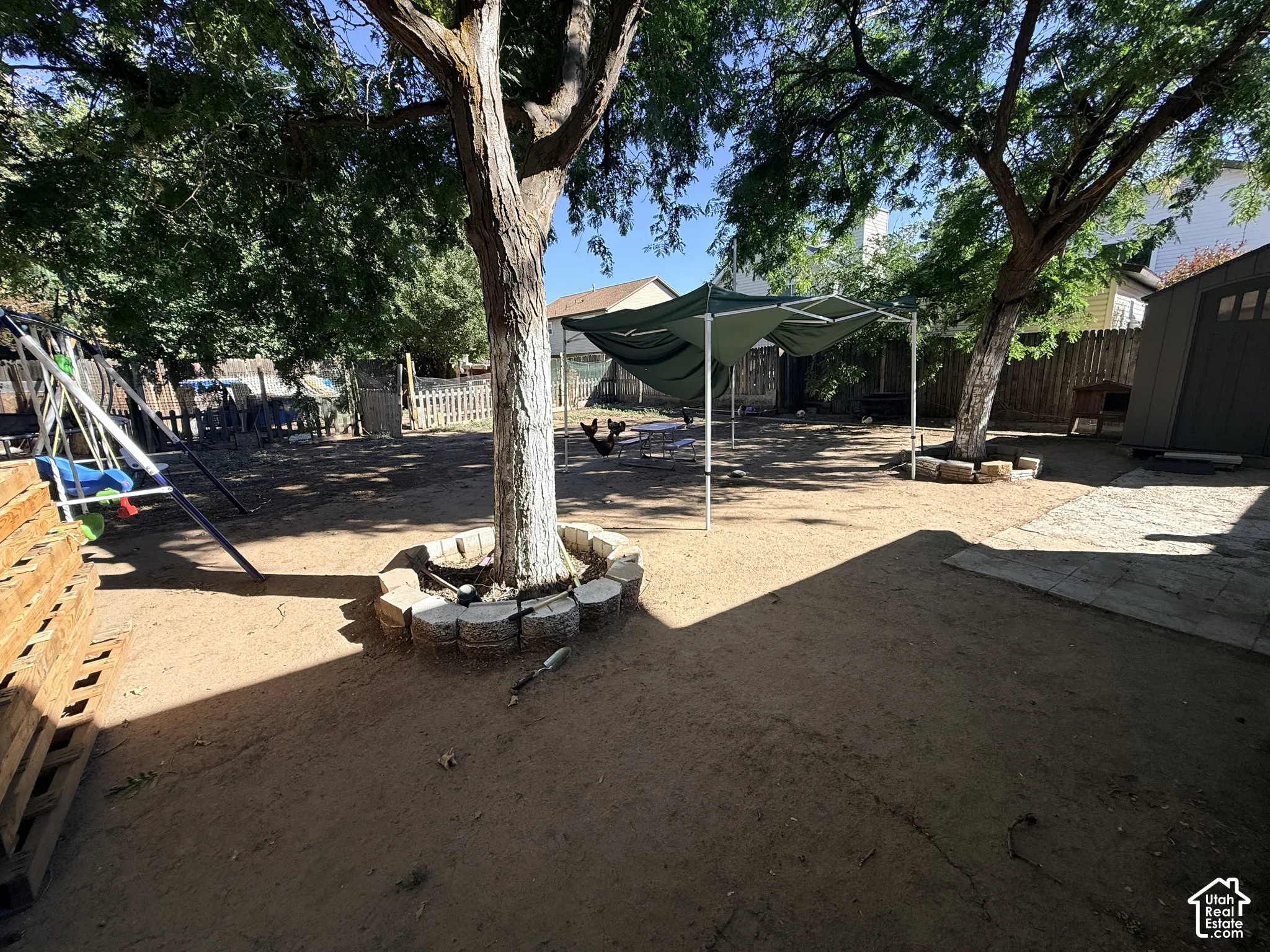 Expansive outdoor space featuring mature trees, a detached storage shed, and durable wood fencing