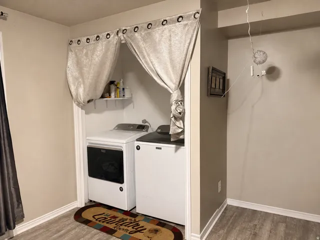 Laundry area with built-in shelving and wood-finish flooring