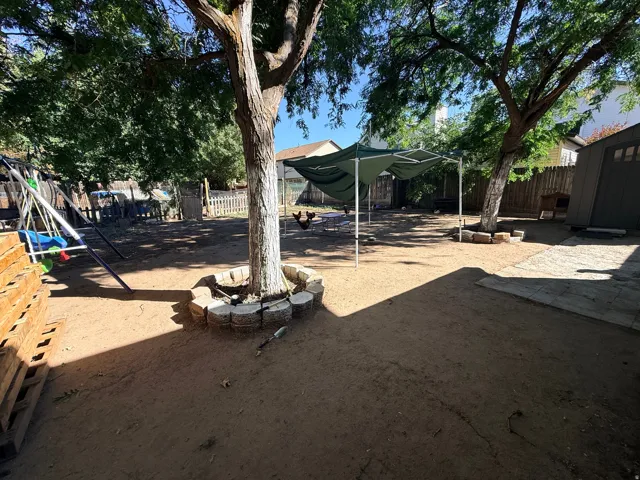 Expansive outdoor space featuring mature trees, a detached storage shed, and durable wood fencing